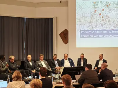 Mehrere Menschen sitzen auf einer Bühne und diskutieren miteinander