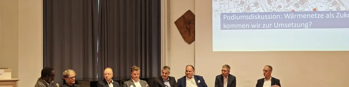 Mehrere Menschen sitzen auf einer Bühne und diskutieren miteinander