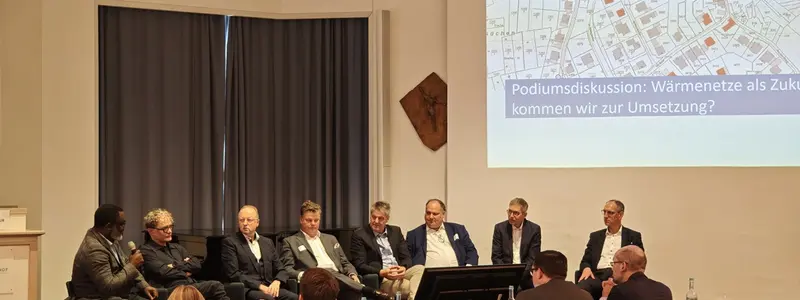 Mehrere Menschen sitzen auf einer Bühne und diskutieren miteinander