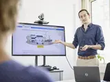 Eine Person steht vor einem Bildschirm und erklärt ein digitales Tool, den Elektroflottenplaner.