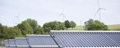 Solarthermie auf Freifläche mit Windrädern im Hintergrund