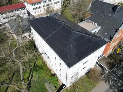 Luftaufnahme eines Großen Gebäudes mit PV-Anlagen auf dem Dach