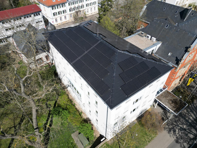 Luftaufnahme eines Großen Gebäudes mit PV-Anlagen auf dem Dach