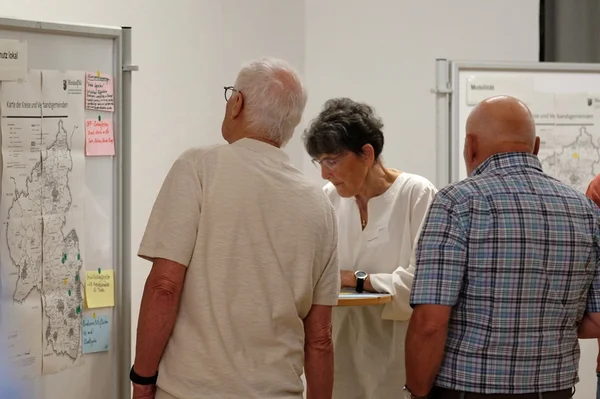 Drei Personen sehen sich auf einem Flipcharte eine Karte von RLP mit Notizen an