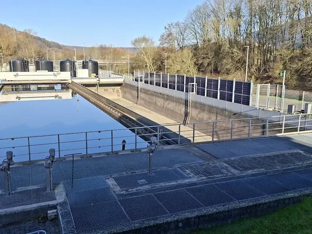 Kläranlage mit Zaun, an dem Solarmodule befestigt sind