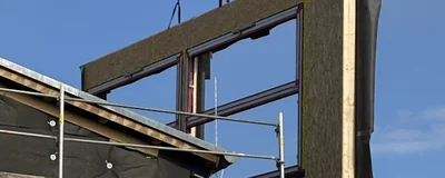 Ein Kran bringt ein Fenster-Fassadenteil an einem Gebäude an, welches seriell saniert wird.