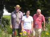 Drei Personen in einem Blühstreifen mit bunten Blumen