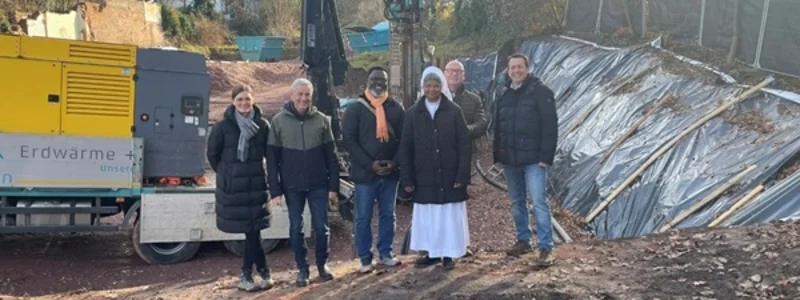 Mehrere Menschen stehen auf einer Baustelle vor einem Bohrgerät