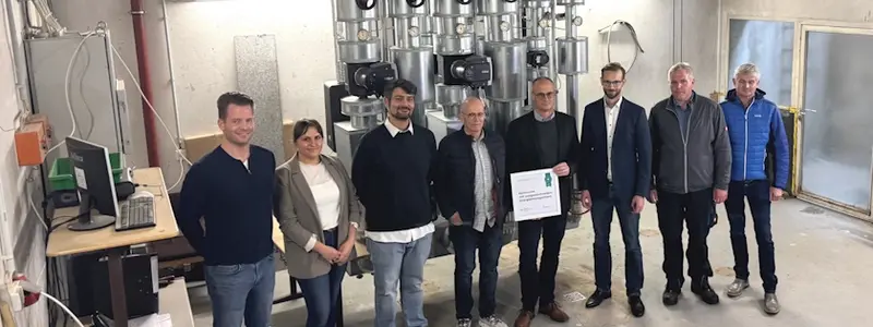 Verschiedene, am Projekt beteiligte Menschen, stehen im Heizungskeller der Heinrich-Roth-Schule.