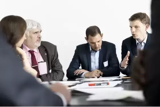 Mehrere Personen sitzen an einem Tisch und diskutieren miteinander