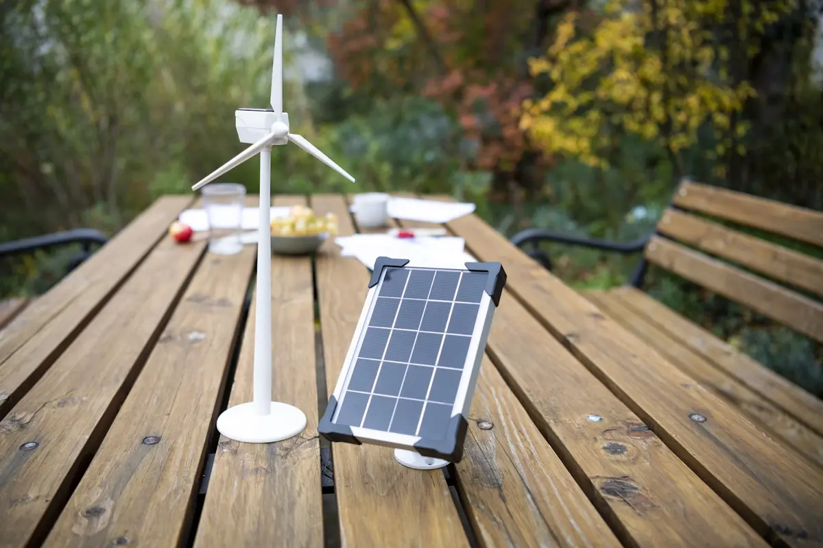 Auf einem Tisch steht ein Modell eines Windrades und eines PV Modules