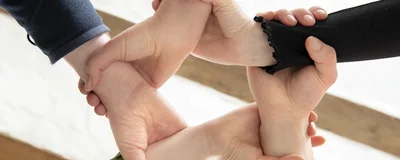 Das Foto zeigt Personen im Kreis die sich die Hände fassen