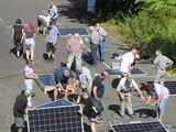 Mehrere Menschen arbeiten draußen mit PV-Modulen