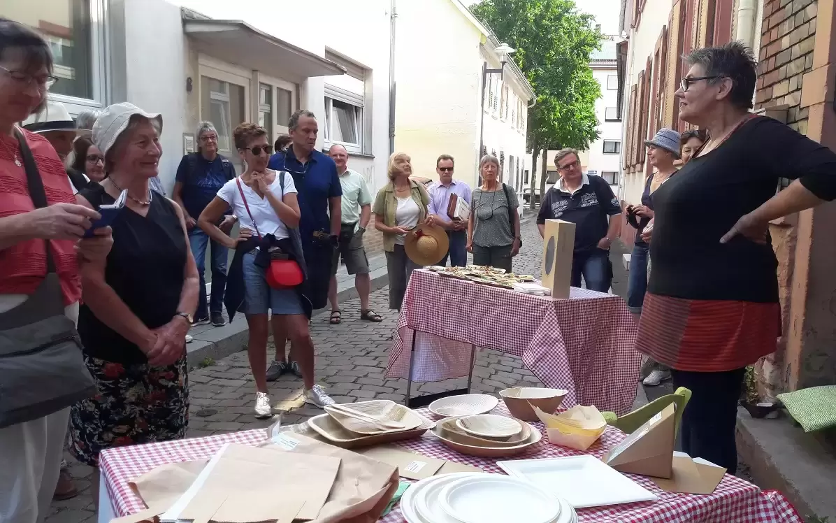 Menschen stehen um Stand herum, hören einer Frau zu