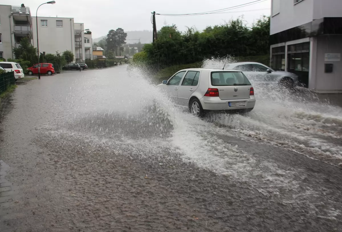 Überschwemmte Straße, durch die ein Auto fährt