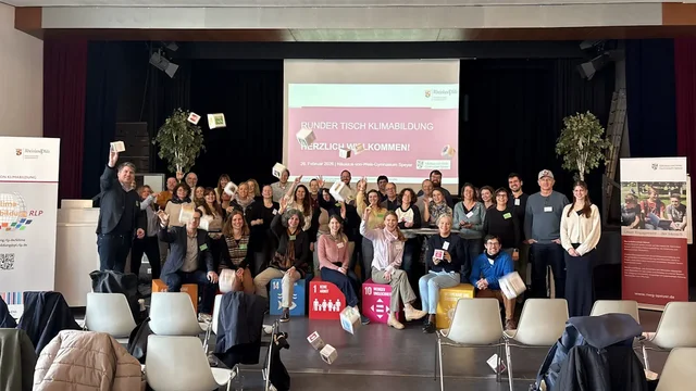 Viele Menschen stehen beisammen und schauen lachend in die Kamera