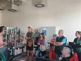 Mehrere Menschen schauen einem Mann zu, der an einer Maschine etwas erklärt