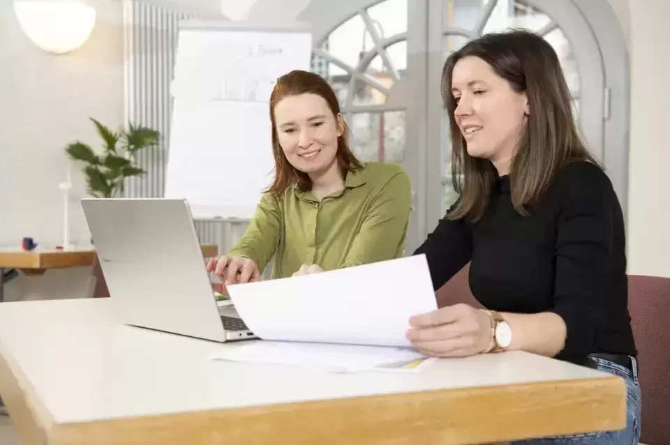 Zwei Mitarbeiterinnen besprechen sich am Laptop