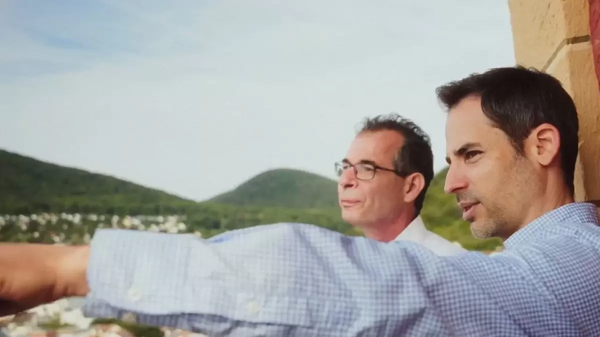 Standbild aus dem Imagevideo der Energieagentur: Zwei Männer stehen auf einem Turm. Ein Mann zeigt dem anderen Mann mit seiner Hand ein Ziel in der Ferne. Im Hintergrund ist der Pfälzer Wald zu sehen.