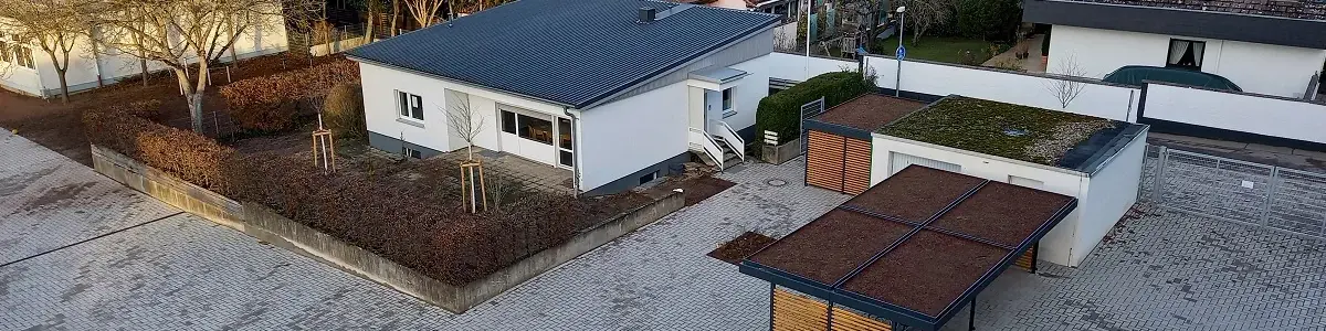 Blick von oben auf einen Schulhof mit begrüntem Dach über Mülleimern