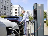 Eine Person steht an einer Ladesäule und setzt den Ladestecker in einen E-Pkw