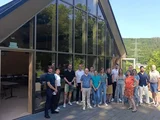 Mehrere Menschen stehen beisammen vor einem Haus und schauen in die Kamera