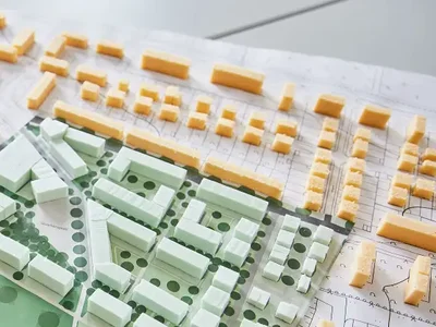 Das Modell einer Stadt liegt auf dem Tisch, daneben das Baugesetzbuch