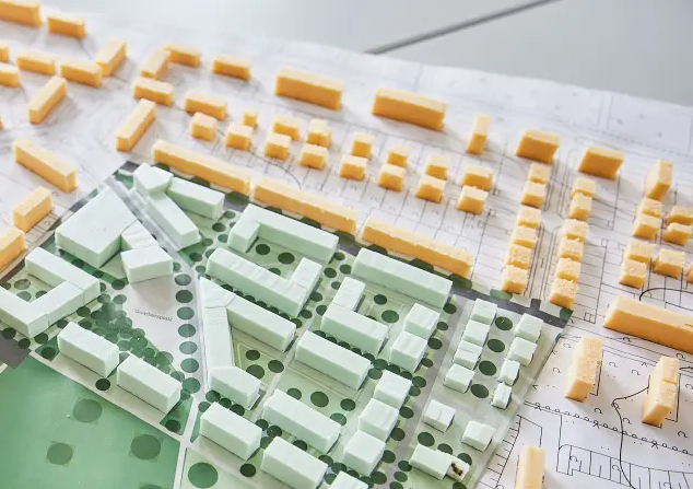 Das Modell einer Stadt liegt auf dem Tisch, daneben das Baugesetzbuch
