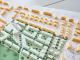 Das Modell einer Stadt liegt auf dem Tisch, daneben das Baugesetzbuch