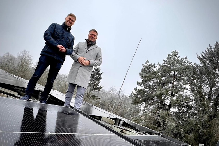 Zwei Menschen stehen bei der PV-Anlage auf dem Dach der Obdachlosenunterkunft. Einer ist der Klimaschutzmanager Marcel Klotz. 