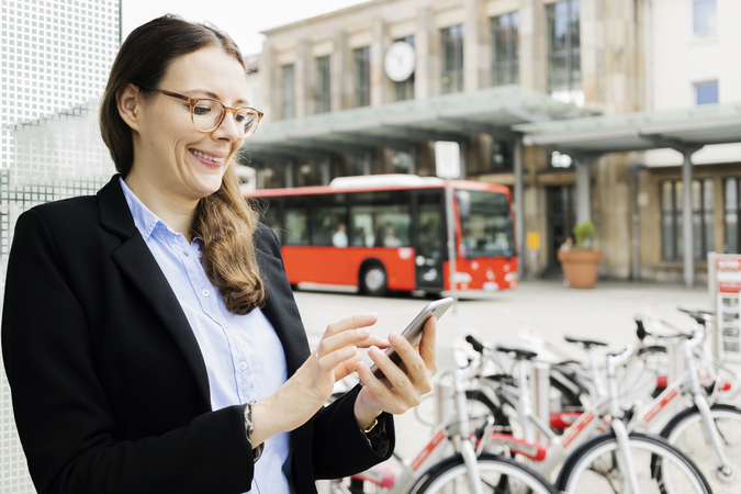 Der Mix macht's: nachhaltige Verkehrsmittel clever miteinander verbinden Person vor Fahrrädern, Bus und Bahnhof