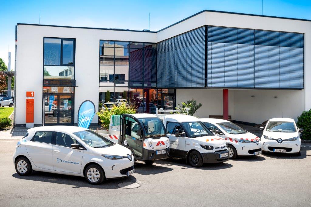 Fahrzeuge mit alternativem Antrieb vor Firmengebäude